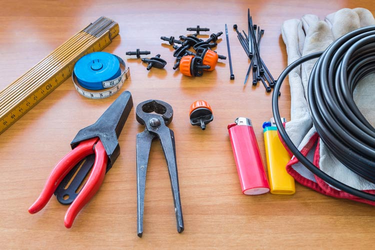 Typical parts for drip irrigation; tube cutter, stakes(in this case zap straps), barbed fittings